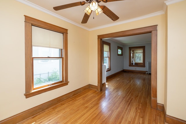 unfurnished room with radiator, light wood-style floors, baseboards, and ornamental molding