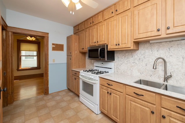 kitchen with a ceiling fan, stainless steel microwave, white gas range, light floors, and a sink