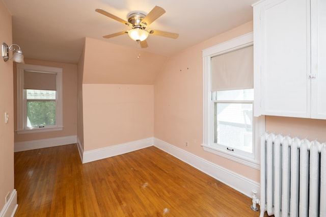 bonus room featuring vaulted ceiling, radiator heating unit, wood finished floors, and baseboards