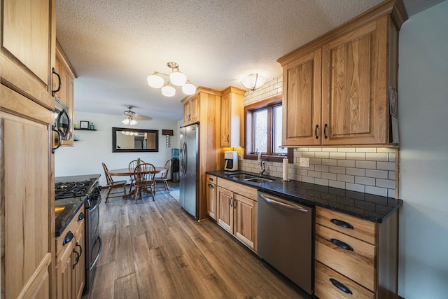 kitchen featuring dark wood-style floors, a sink, stainless steel appliances, a textured ceiling, and backsplash