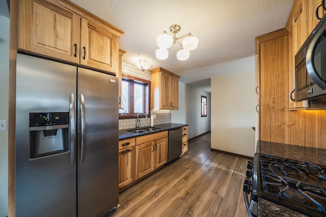 kitchen featuring dark wood-style flooring, a sink, black appliances, tasteful backsplash, and an inviting chandelier