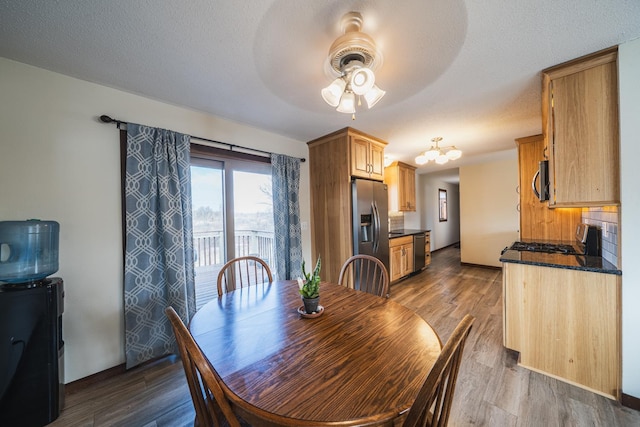 dining space with a ceiling fan, a textured ceiling, and wood finished floors