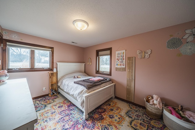 bedroom featuring a textured ceiling, multiple windows, visible vents, and baseboards