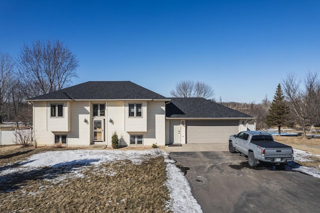 split foyer home with a garage, aphalt driveway, and a shingled roof