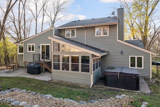 back of house with a patio area, a chimney, a hot tub, and a shingled roof