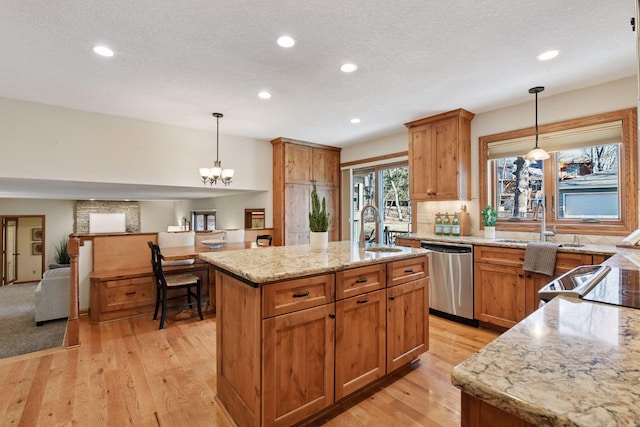 kitchen featuring light stone countertops, a center island with sink, a sink, stainless steel dishwasher, and open floor plan