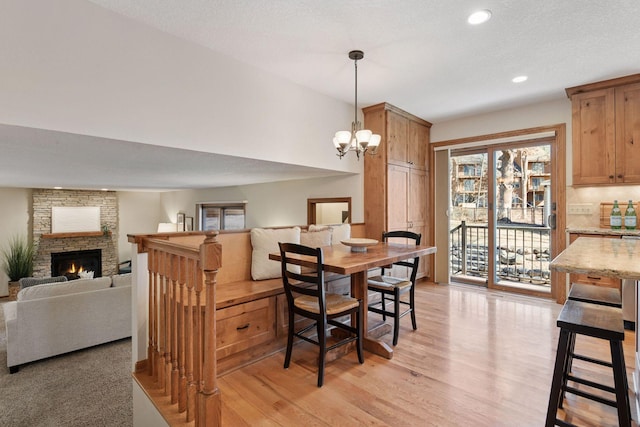 dining area featuring a notable chandelier, recessed lighting, a fireplace, and light wood-style floors