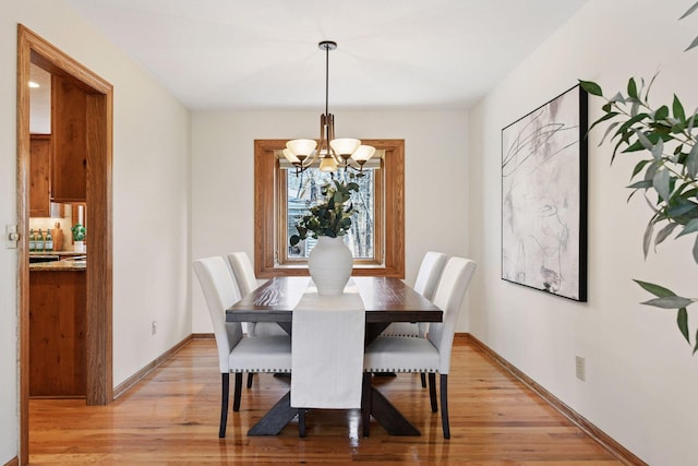 dining room with light wood-type flooring, baseboards, and a chandelier