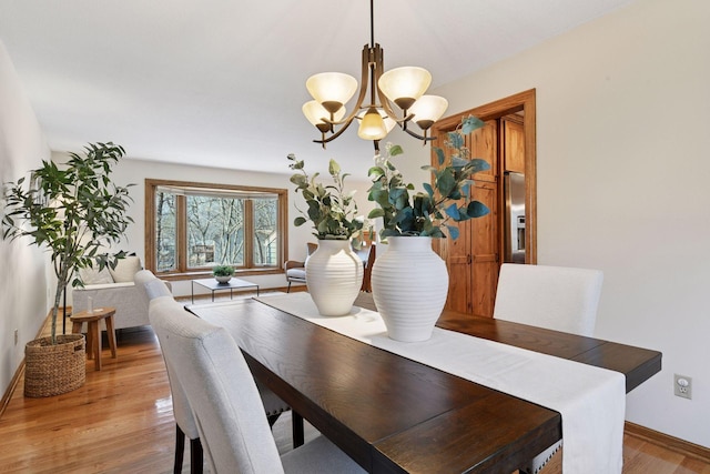 dining area with a chandelier, light wood-style flooring, and baseboards