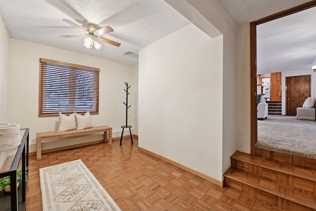 hall featuring baseboards, a textured ceiling, and stairs