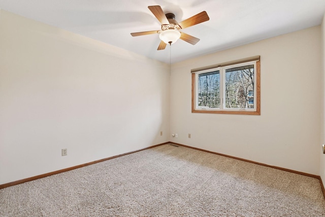 carpeted spare room featuring baseboards and ceiling fan