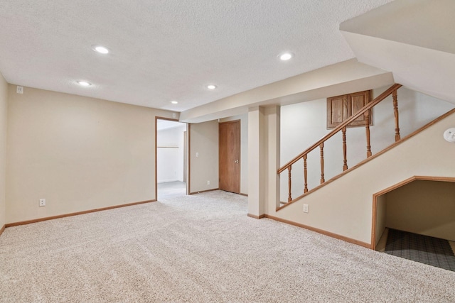 finished basement featuring stairway, a textured ceiling, baseboards, and carpet floors