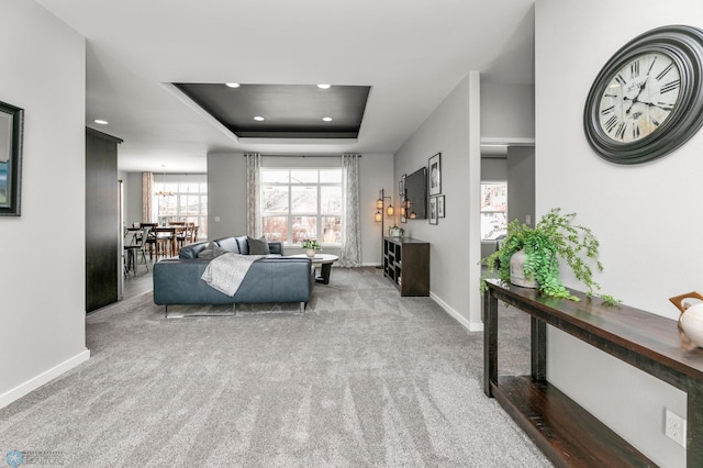 carpeted living area featuring a tray ceiling, baseboards, and recessed lighting