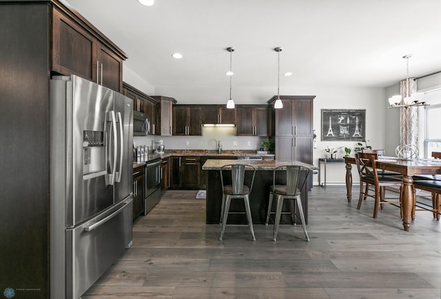 kitchen with a kitchen island, dark wood-style flooring, stainless steel appliances, dark brown cabinets, and a sink