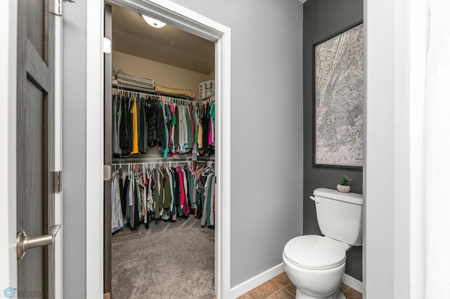 bathroom featuring toilet, a spacious closet, and baseboards