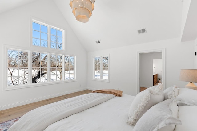 bedroom featuring high vaulted ceiling, wood finished floors, visible vents, and baseboards