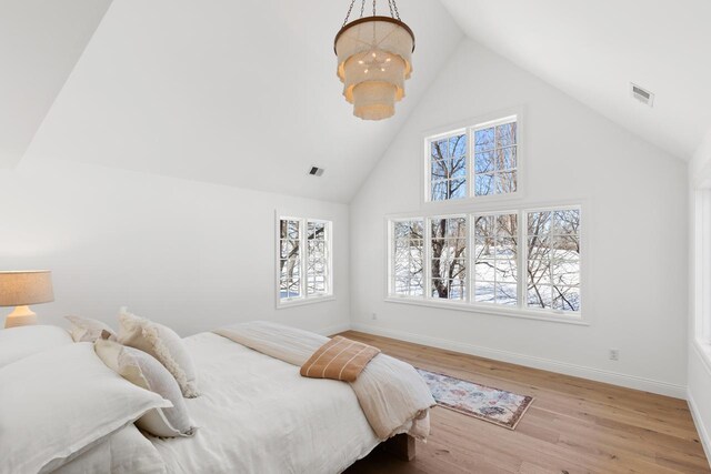 bedroom featuring high vaulted ceiling, visible vents, multiple windows, and wood finished floors