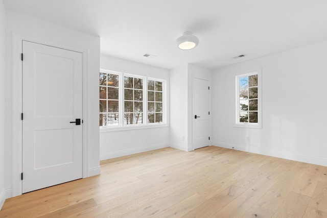 spare room with light wood finished floors, visible vents, and baseboards