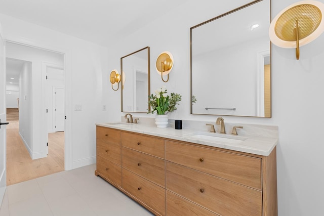 bathroom with double vanity, a sink, and baseboards