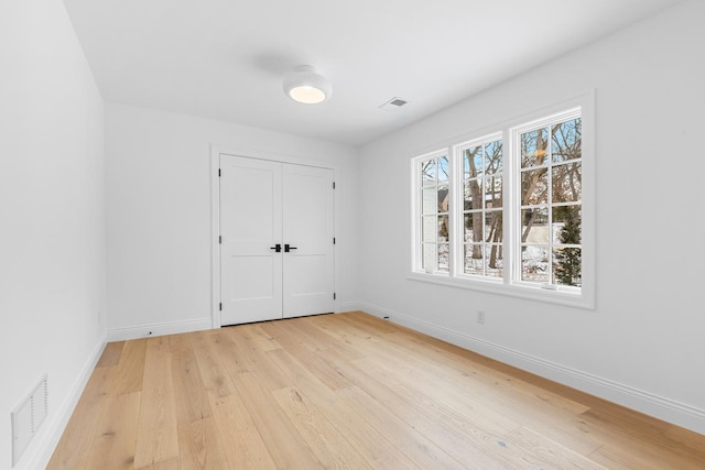 unfurnished bedroom with light wood finished floors, baseboards, and visible vents