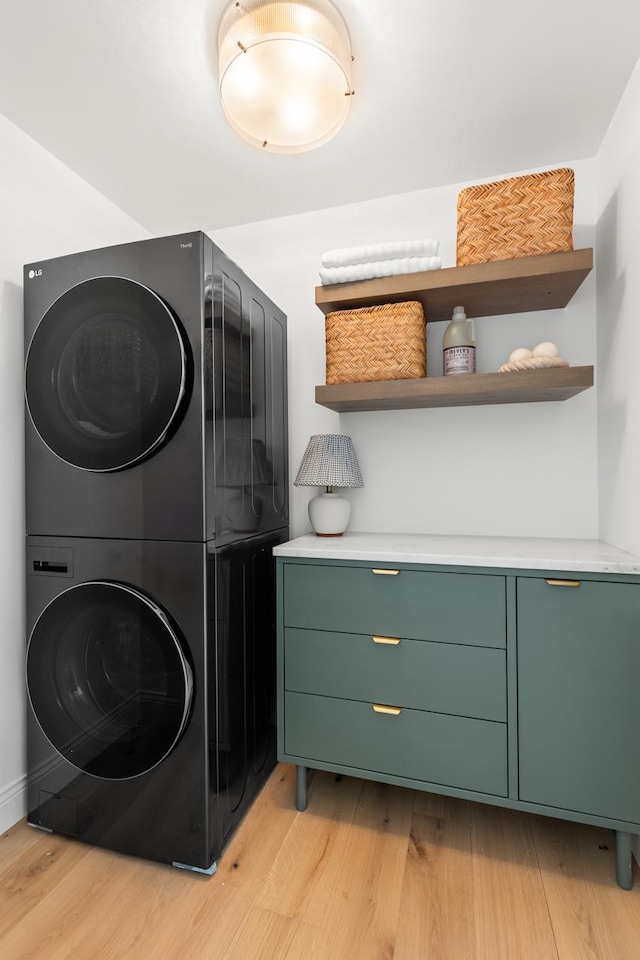 washroom featuring laundry area, stacked washer / dryer, and light wood-style flooring