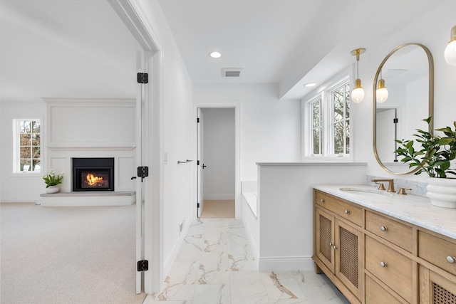 bathroom featuring marble finish floor, visible vents, a glass covered fireplace, vanity, and baseboards