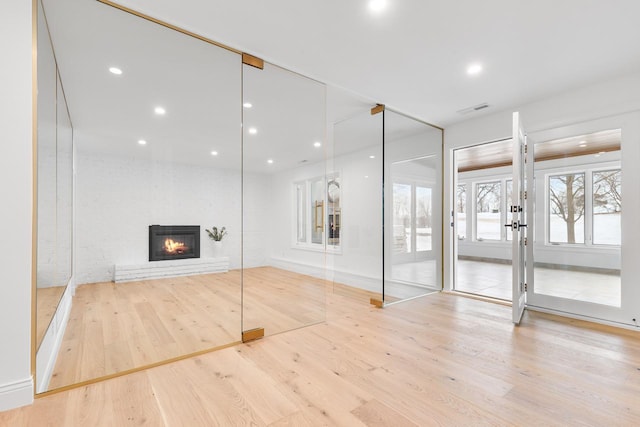 workout room featuring a glass covered fireplace, visible vents, light wood-style flooring, and recessed lighting