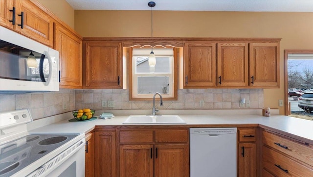 kitchen featuring light countertops, white appliances, brown cabinets, and a sink