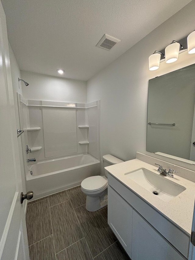 bathroom with a textured ceiling, toilet, vanity, visible vents, and tub / shower combination