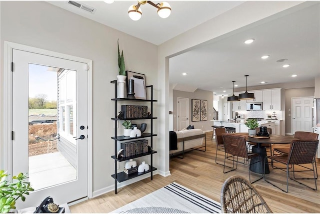 dining space with light wood finished floors, recessed lighting, visible vents, an inviting chandelier, and baseboards