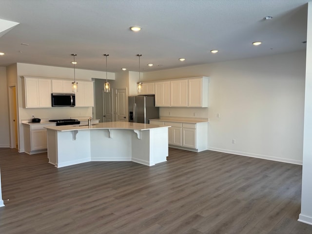 kitchen featuring an island with sink, appliances with stainless steel finishes, white cabinets, and dark wood finished floors