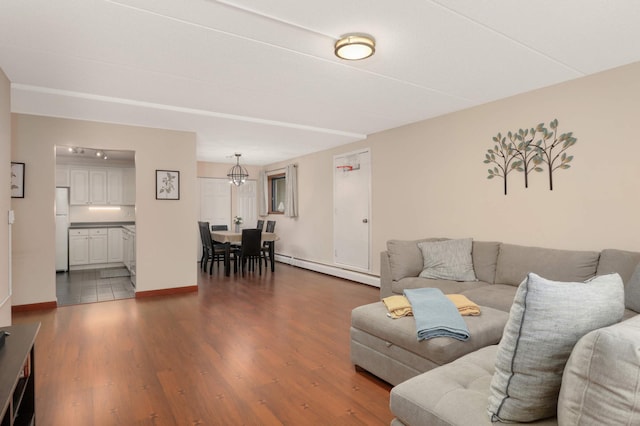 living area with a baseboard radiator, baseboards, dark wood-style floors, and a chandelier