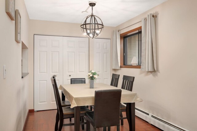 dining room featuring a baseboard heating unit, a notable chandelier, and dark wood finished floors