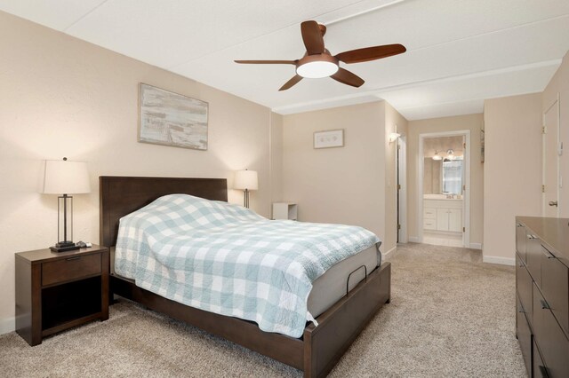 bedroom featuring a ceiling fan, baseboards, ensuite bathroom, and light carpet