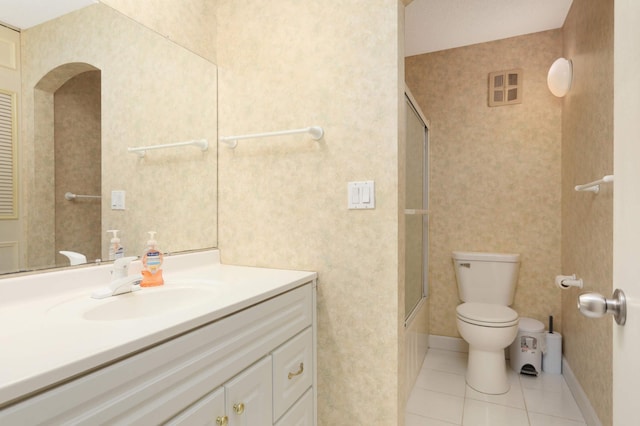 bathroom featuring baseboards, toilet, tile patterned floors, vanity, and enclosed tub / shower combo