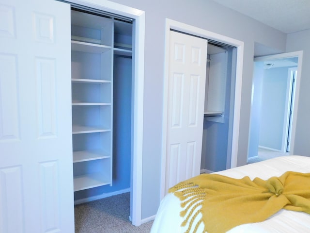 bedroom with multiple closets, carpet flooring, and baseboards