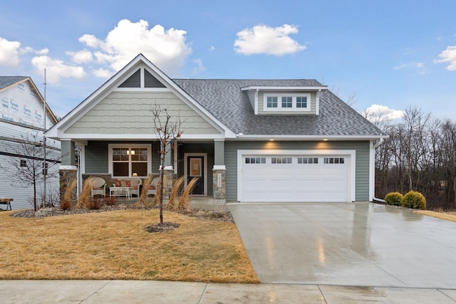 craftsman inspired home with roof with shingles, covered porch, concrete driveway, an attached garage, and a front lawn