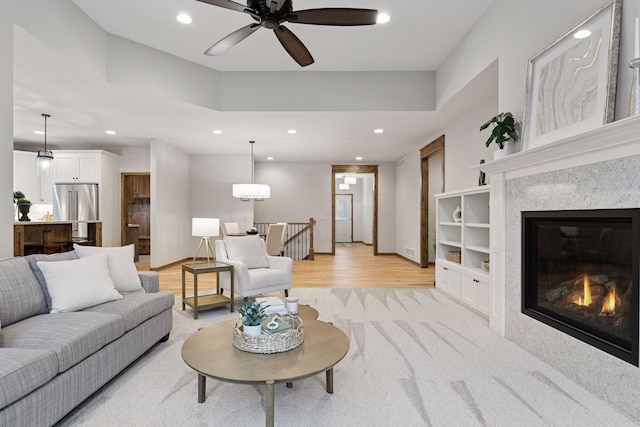 living room featuring light wood-style flooring, visible vents, a glass covered fireplace, and recessed lighting