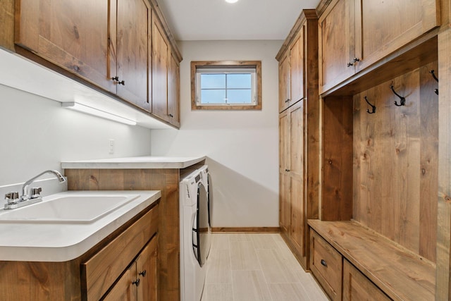 laundry area featuring cabinet space, a sink, baseboards, and separate washer and dryer