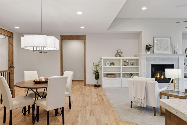 dining room featuring recessed lighting, a glass covered fireplace, and light wood-style floors