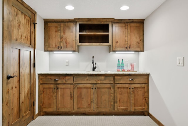 kitchen featuring light countertops, brown cabinets, a sink, and open shelves