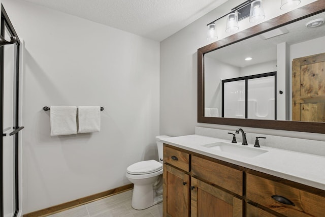 bathroom with toilet, vanity, a shower stall, a textured ceiling, and baseboards