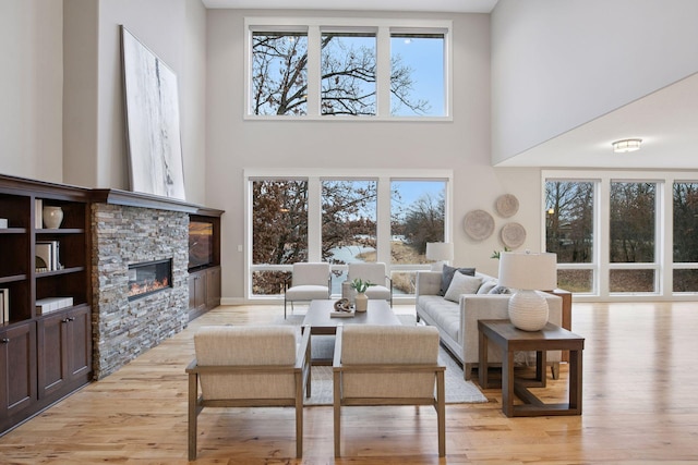 18928 Katrine Ct, Lakeville, MN 55044 - living room featuring a towering ceiling, a fireplace, light wood-style flooring, and healthy amount of natural light