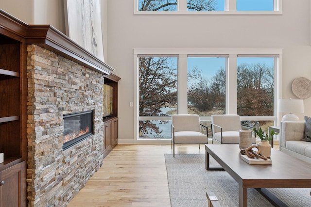 18928 Katrine Ct, Lakeville, MN 55044 - living room with a stone fireplace, light wood-style flooring, a towering ceiling, and plenty of natural light