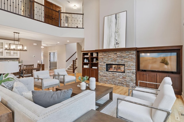 18928 Katrine Ct, Lakeville, MN 55044 - living room with wood finished floors, stairs, a stone fireplace, a high ceiling, and a chandelier