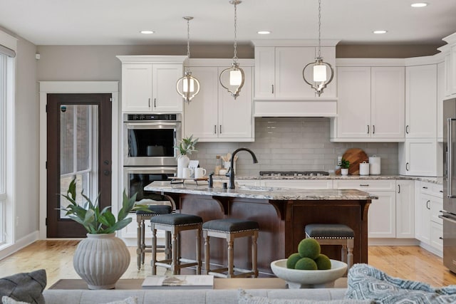 18928 Katrine Ct, Lakeville, MN 55044 - kitchen with appliances with stainless steel finishes, light wood finished floors, white cabinetry, tasteful backsplash, and recessed lighting