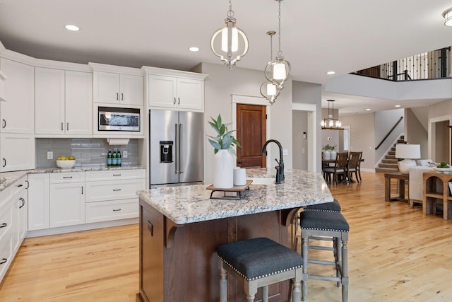 18928 Katrine Ct, Lakeville, MN 55044 - kitchen with appliances with stainless steel finishes, a sink, white cabinets, light wood-style flooring, and recessed lighting