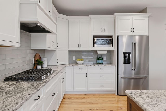 18928 Katrine Ct, Lakeville, MN 55044 - kitchen with appliances with stainless steel finishes, custom exhaust hood, white cabinetry, and backsplash