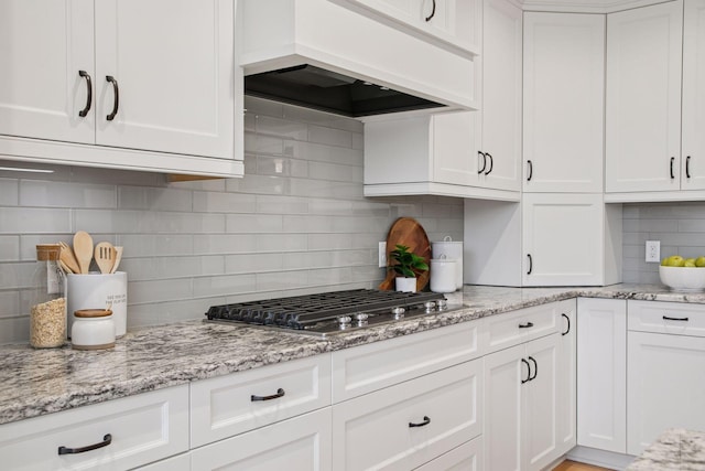 18928 Katrine Ct, Lakeville, MN 55044 - kitchen featuring custom exhaust hood, decorative backsplash, stainless steel gas stovetop, white cabinets, and light stone countertops