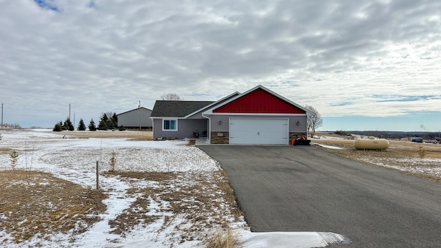 view of front facade featuring a garage, stone siding, and aphalt driveway